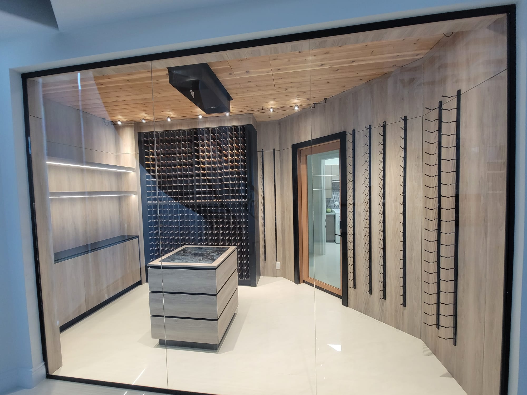 Glass-walled wine cellar with wood paneling, LED shelf lighting, and ceiling spotlights.