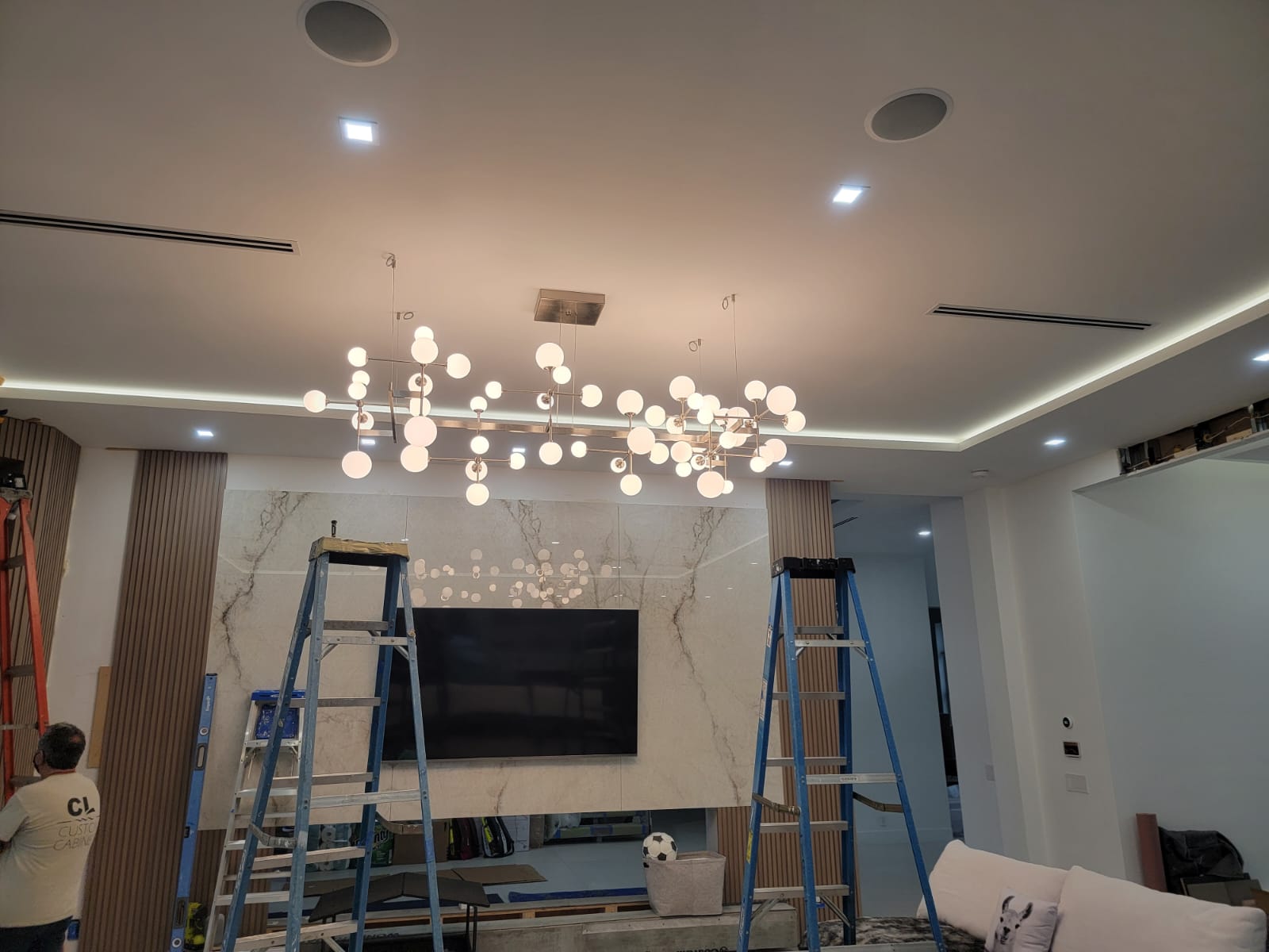 Living room with layered chandelier, cove lighting and recessed spots.