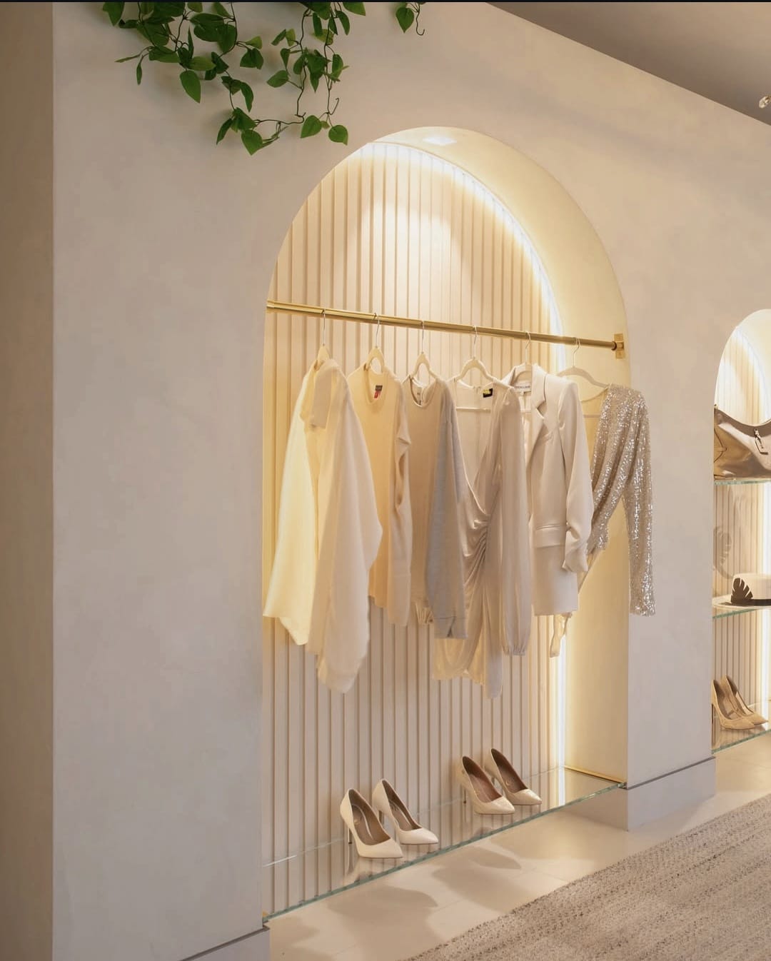Expositor de ropa arqueado e iluminado con estantes.