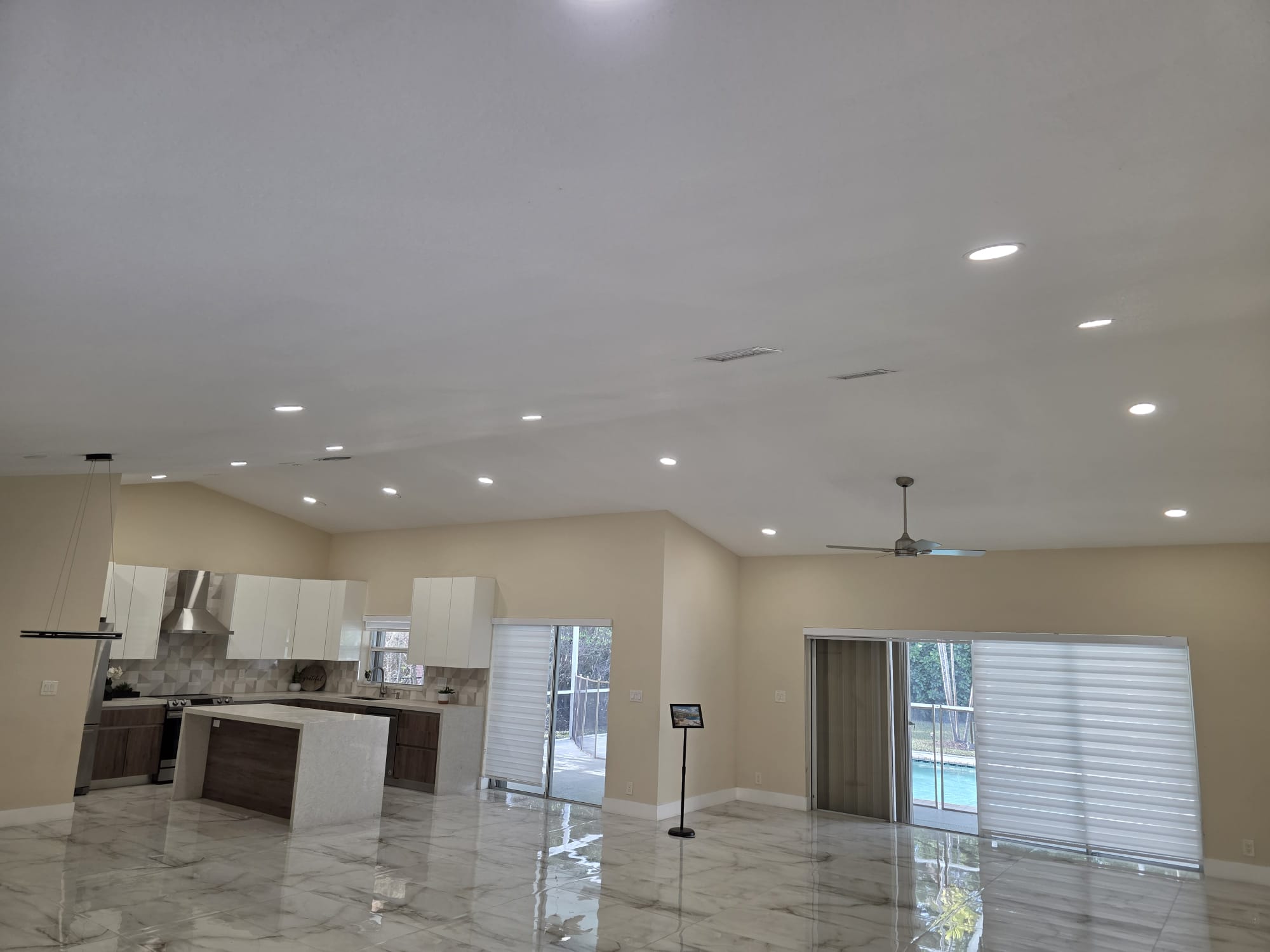 Open-concept kitchen and living room with vaulted recessed lighting and a linear pendant.