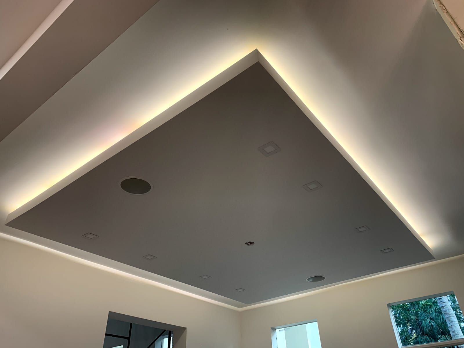 Dropped gray ceiling panel with warm perimeter glow and recessed square lights.